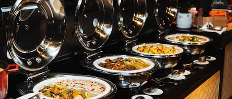 A buffet with multiple food stations, each with a covered serving dish.