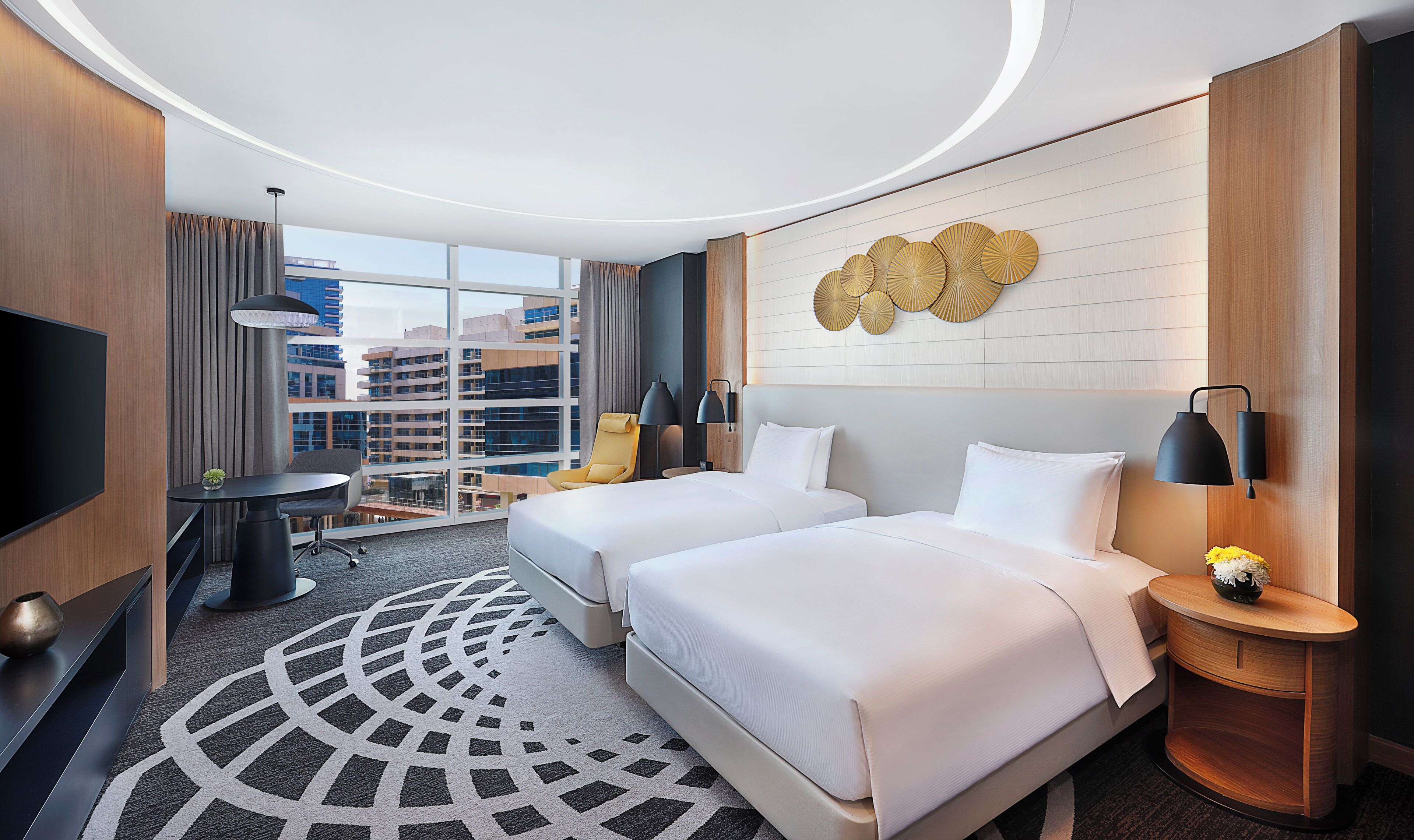 Une chambre d’hôtel avec deux lits, un bureau, une chaise, une télévision et une vue sur le paysage urbain.