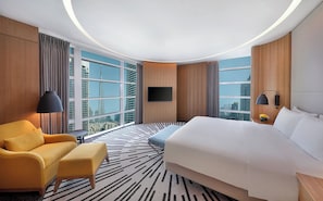 Une chambre d’hôtel avec un lit, un canapé, une télévision et une vue sur la ville.