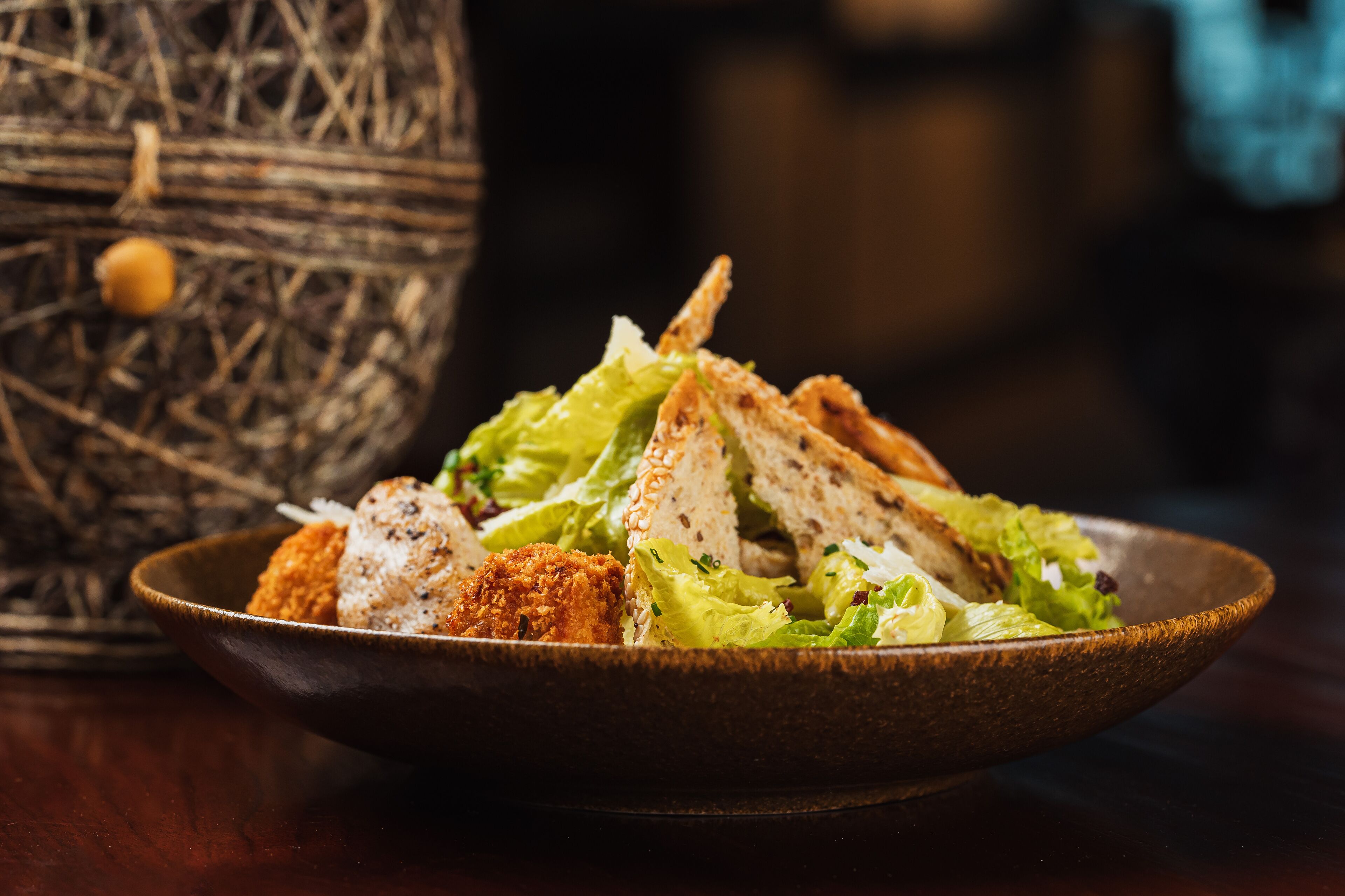 Un bol de salade avec des croûtons et une tranche de pain.