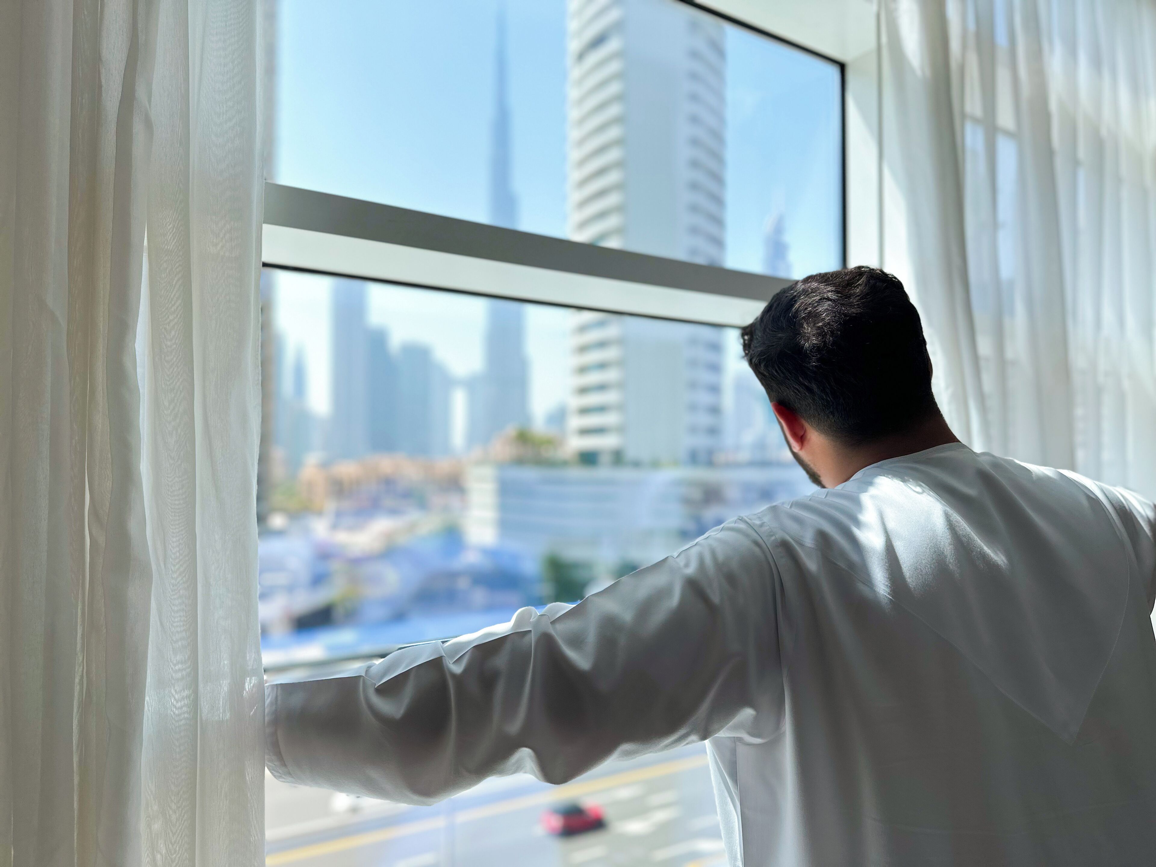 A person looking out of a window with a cityscape view.