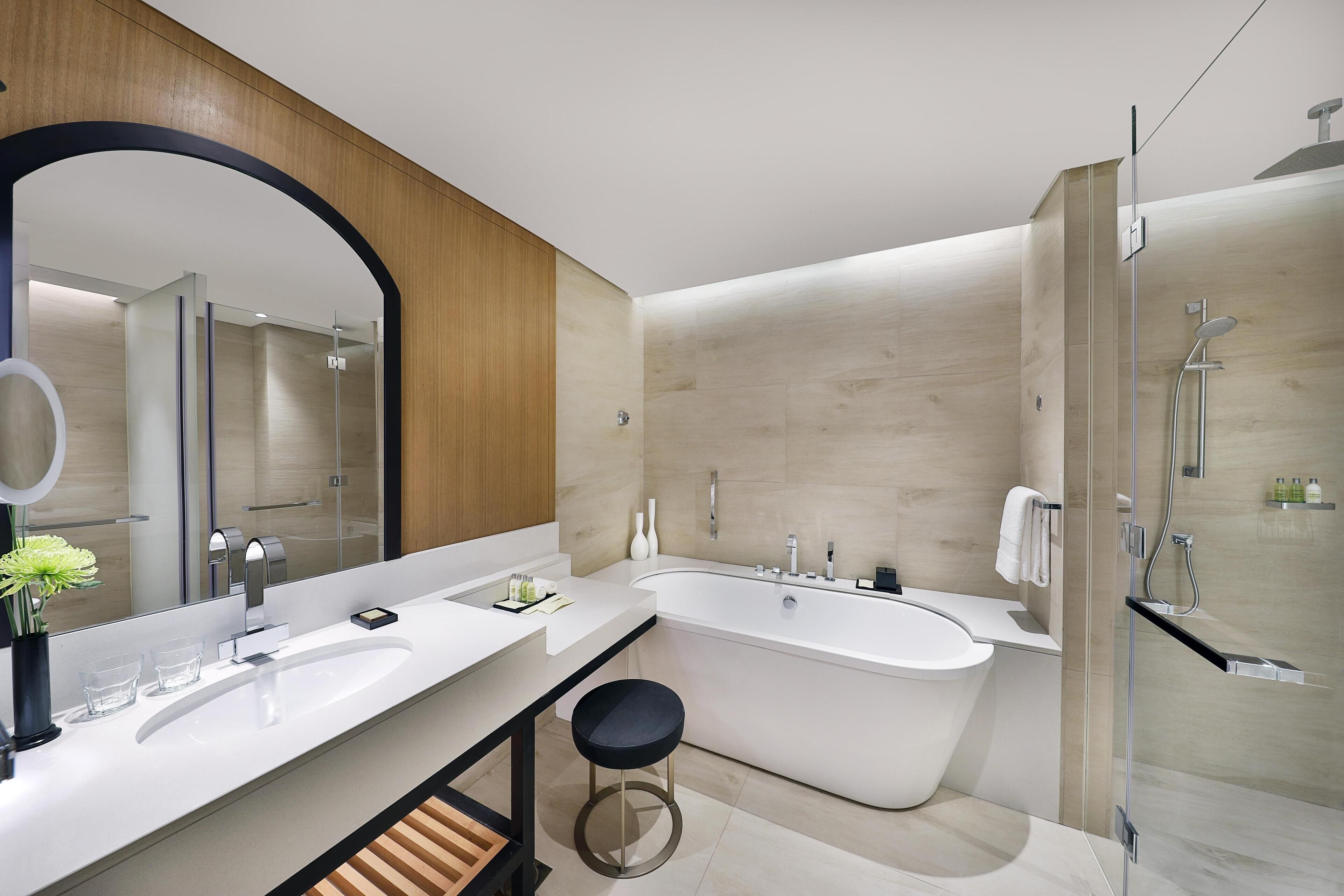A modern bathroom with a large bathtub, a double sink vanity, and a glass-enclosed shower area.