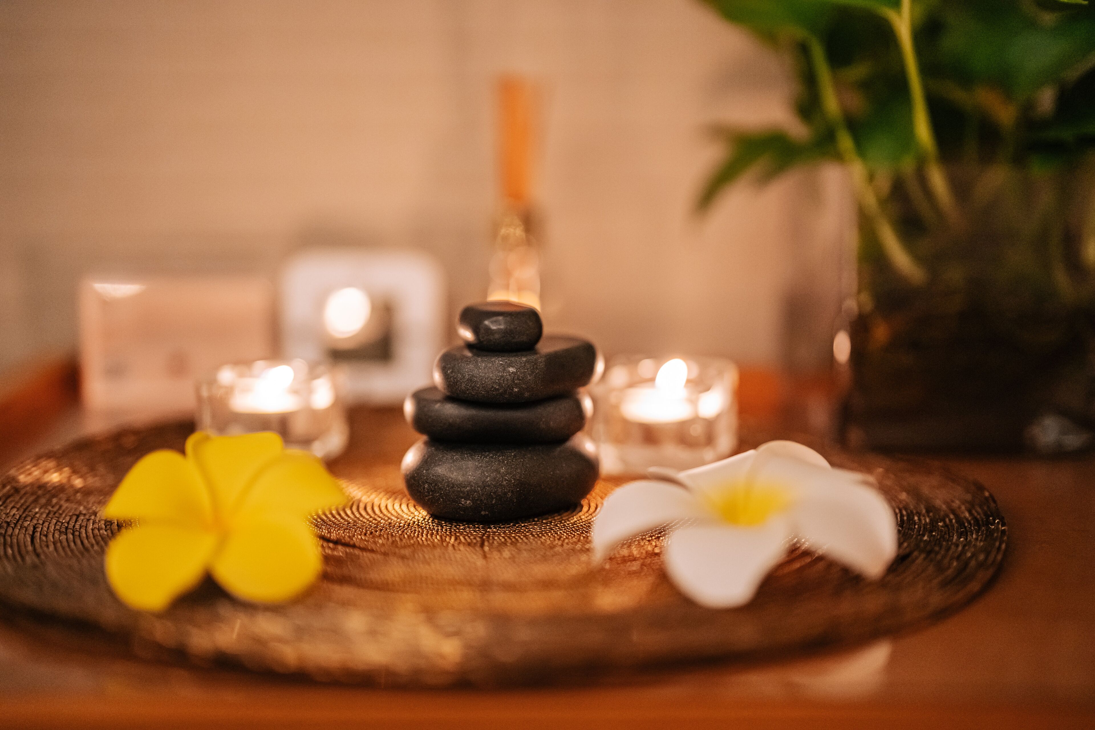 A stack of stones, candles, and flowers on a textured surface.