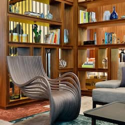 Relax in this inviting living space with a comfortable sofa, unique chair, and plenty of books to enjoy.