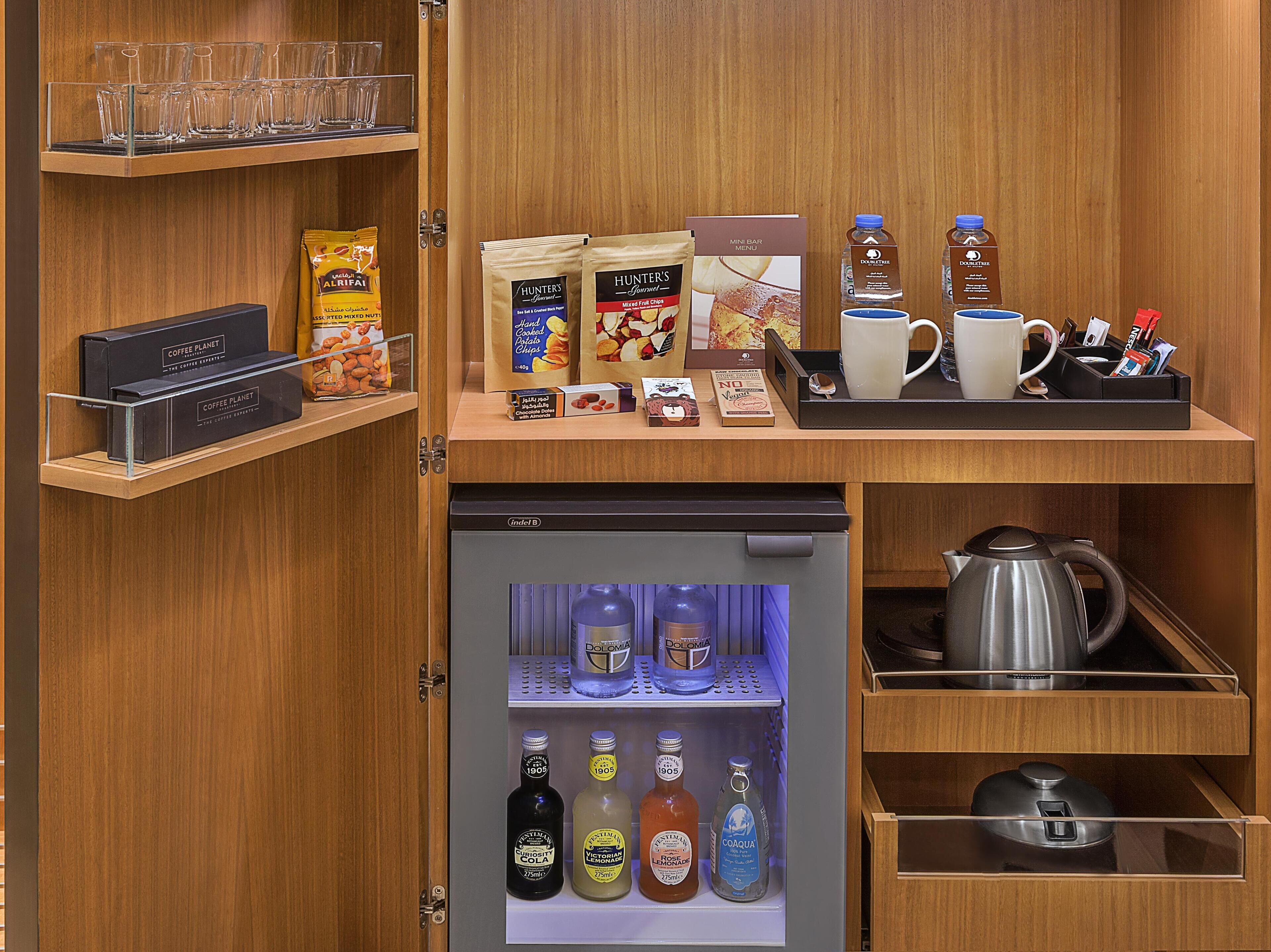 A minibar with snacks, coffee, tea, and bottled beverages.