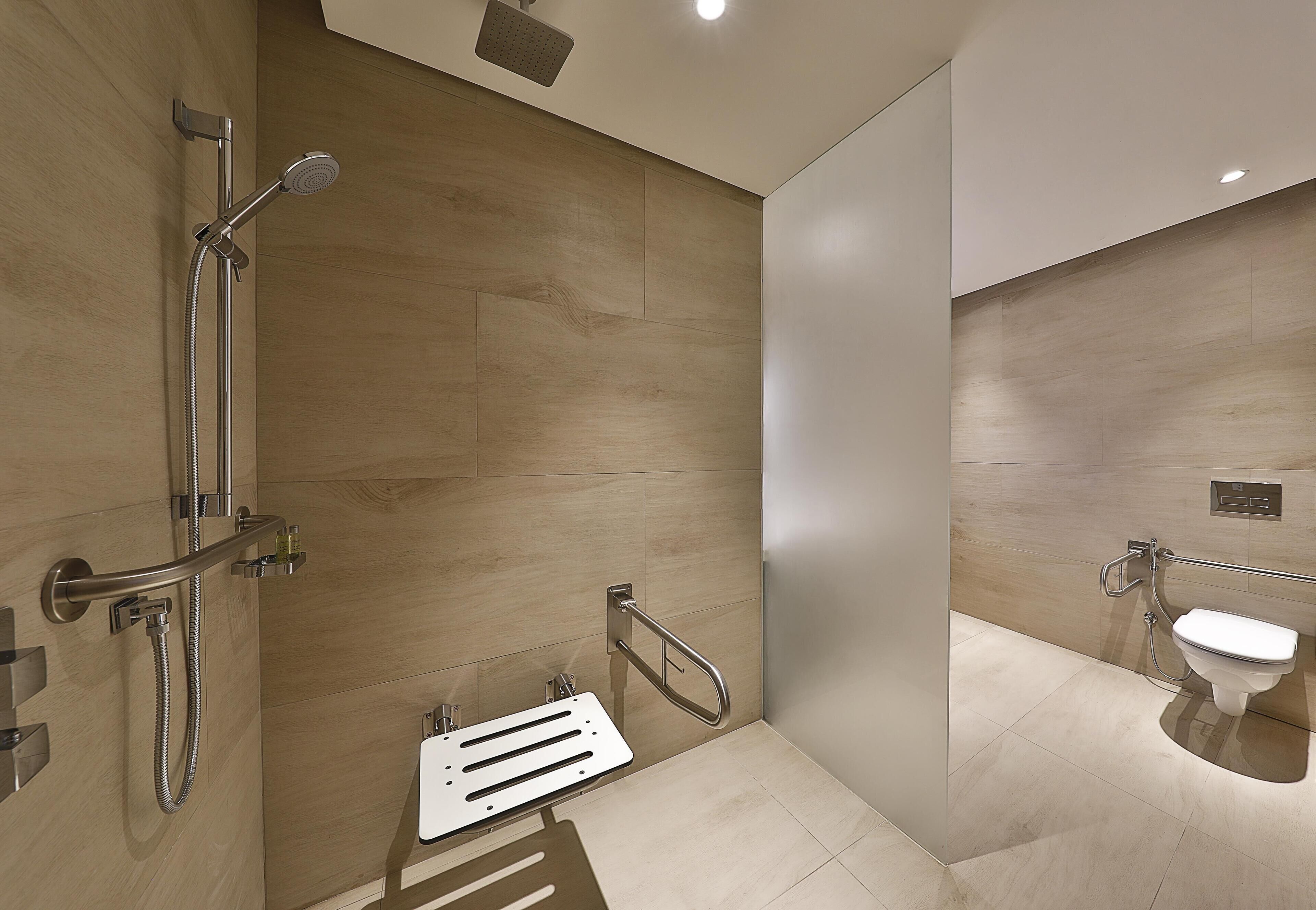 Une salle de bain moderne équipée d’une douche, de toilettes et de barres d’appui.