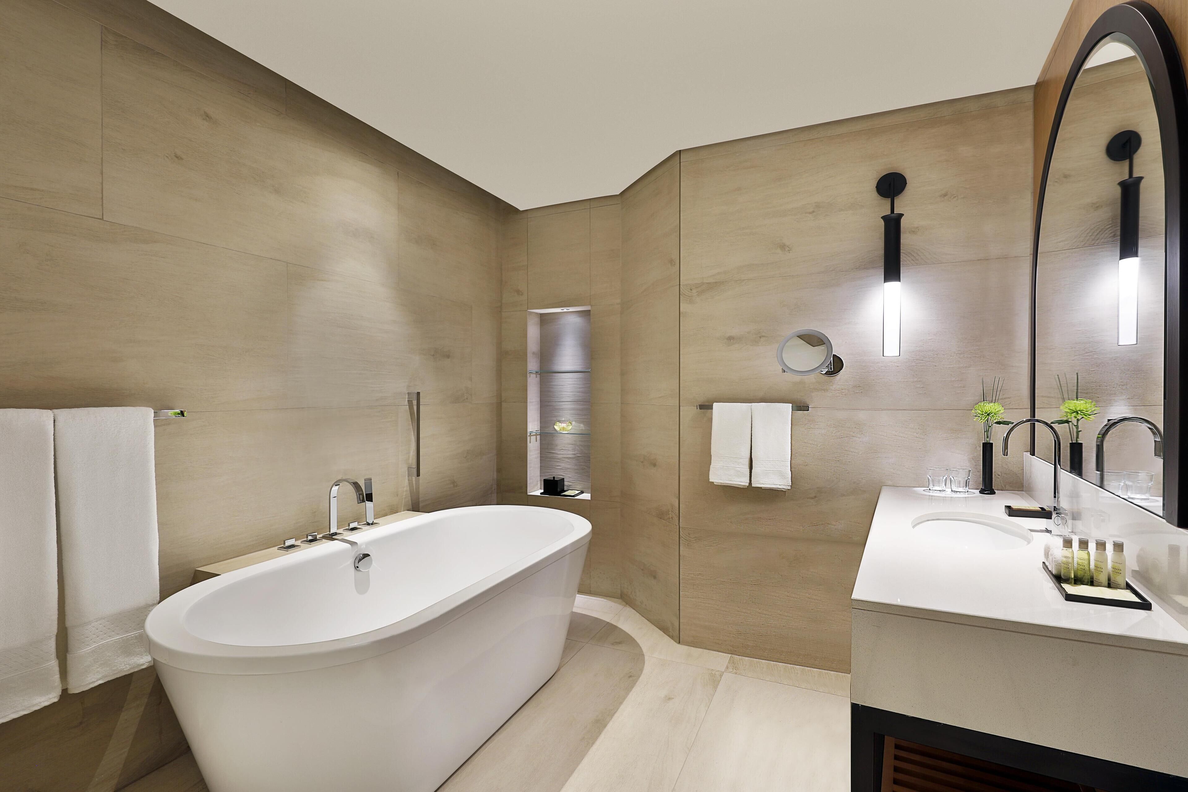 Un baño moderno con una bañera independiente, un tocador con espejo y un perchero para toallas.