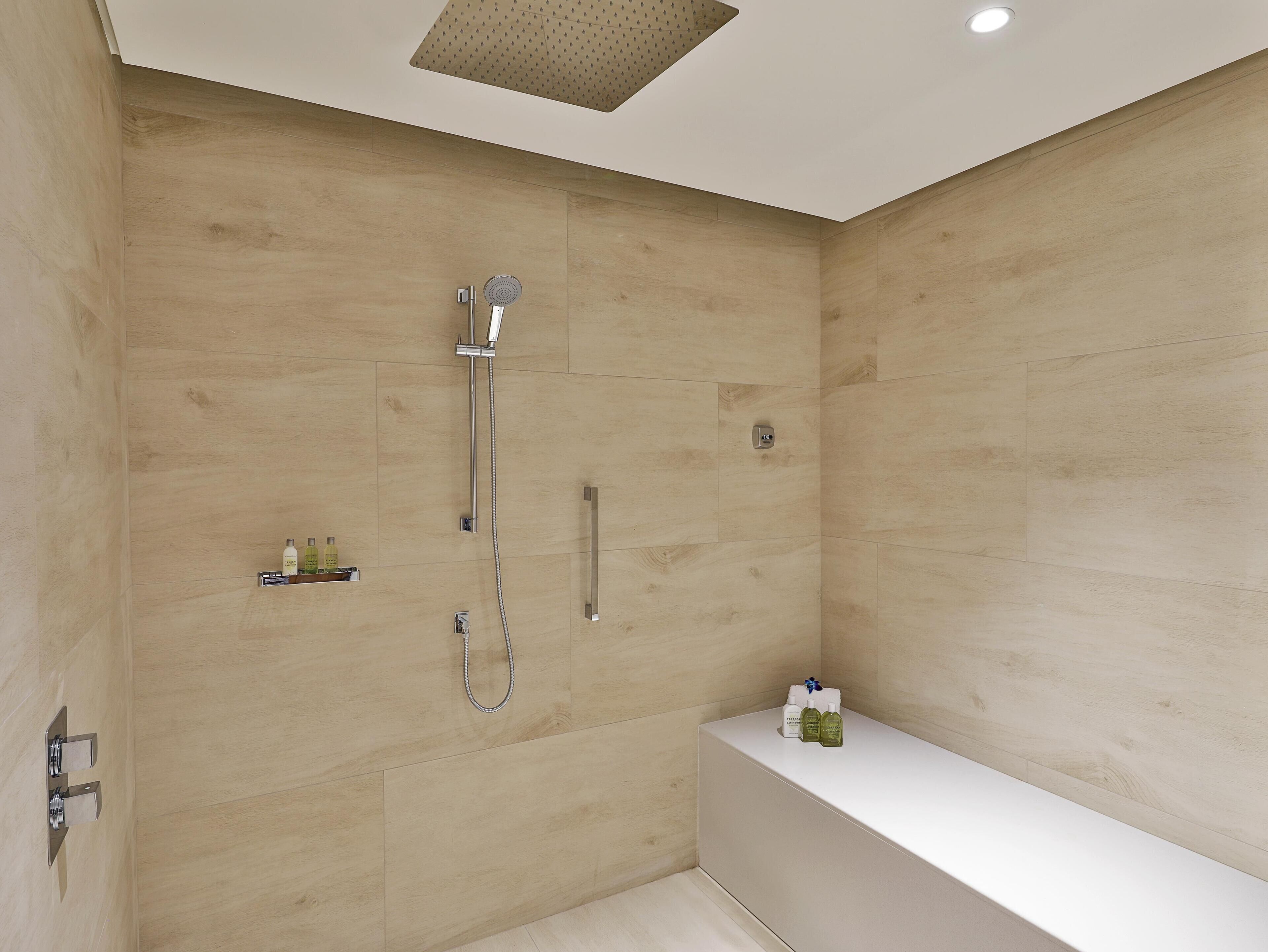 A modern bathroom with a shower, a bathtub, and a shelf with toiletries.