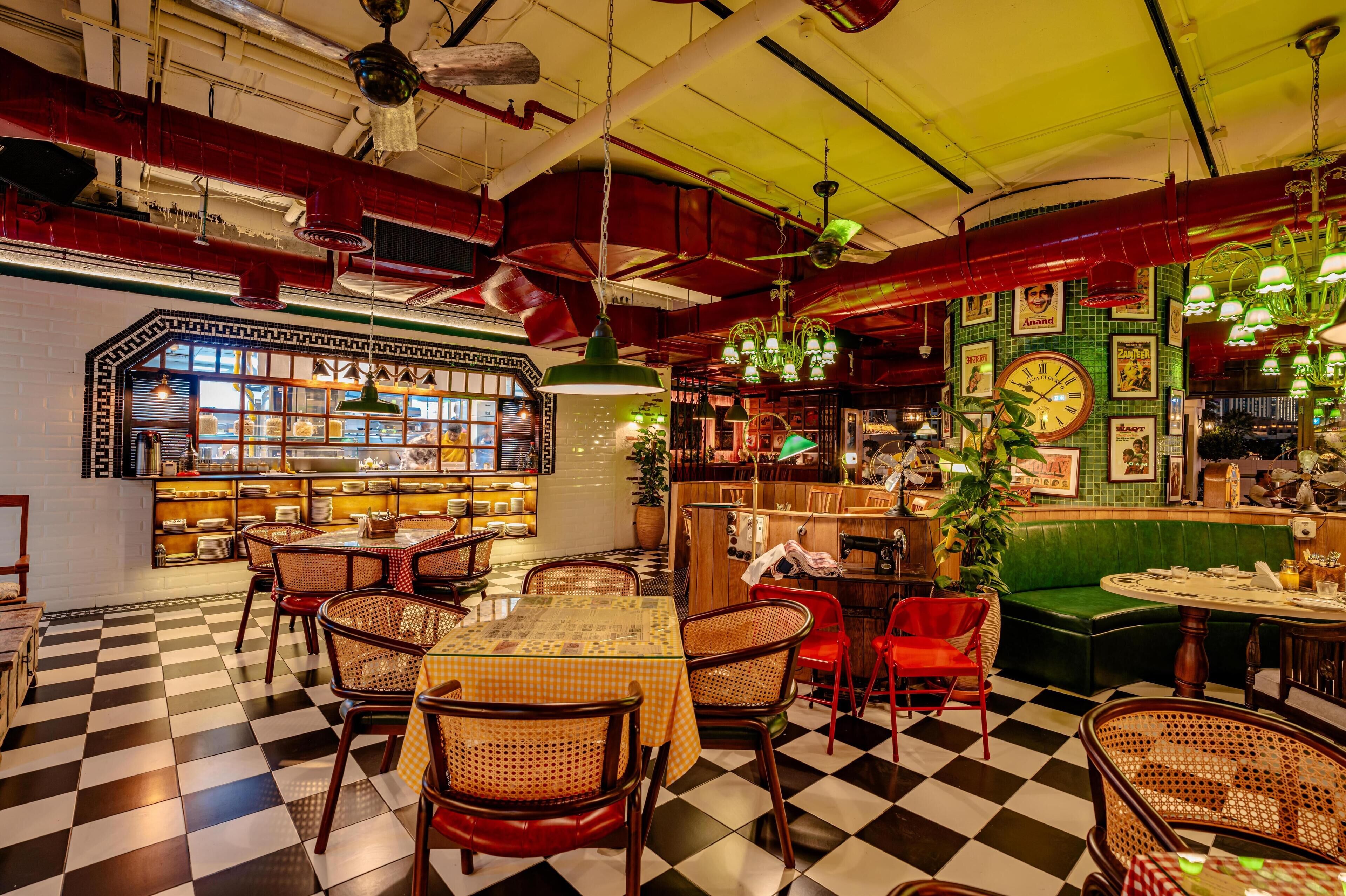 A restaurant with checkered flooring, wicker chairs, a bar area, and various hanging lights.