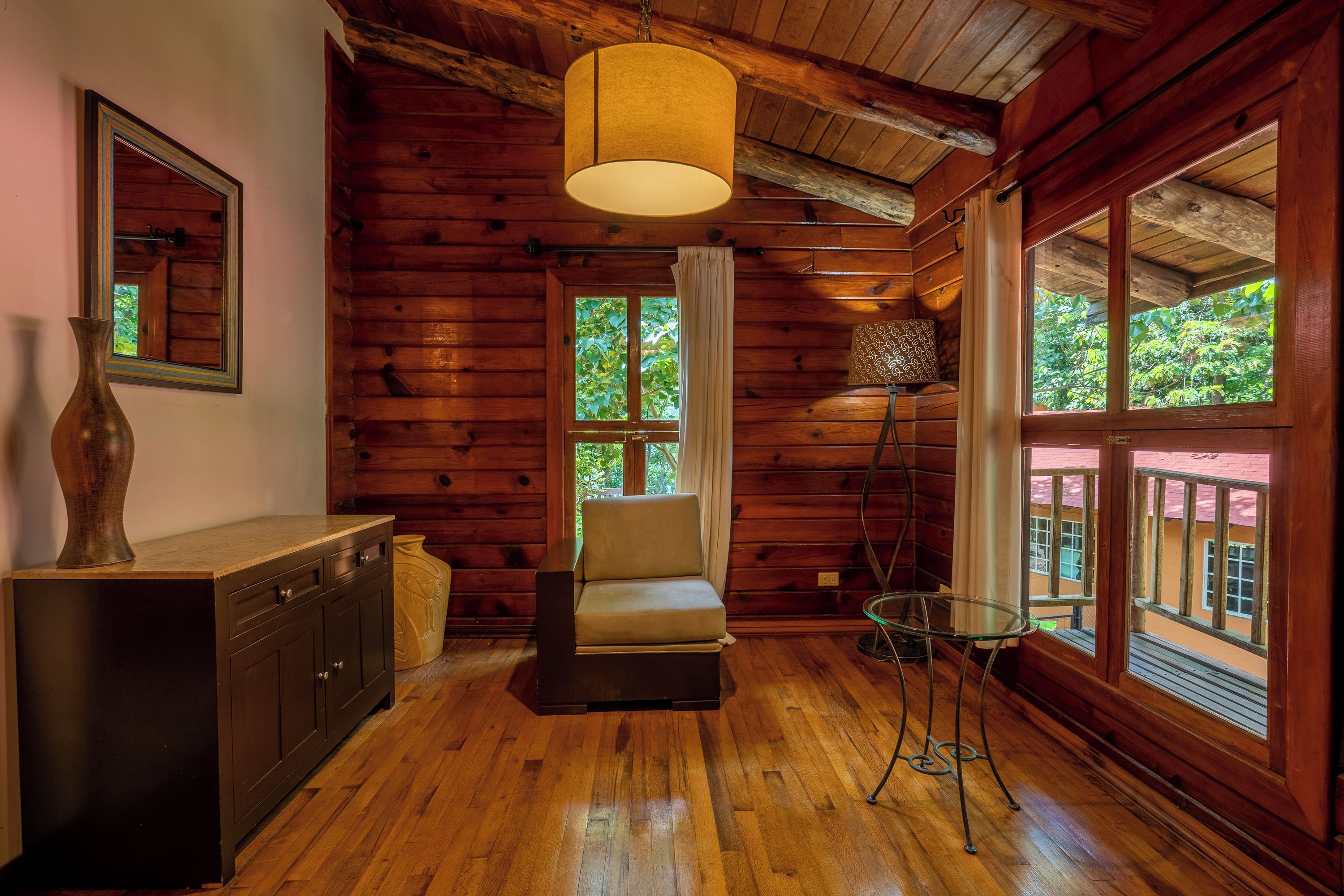 Interior de una cabaña de madera con un sofá, una mesa y un armario.