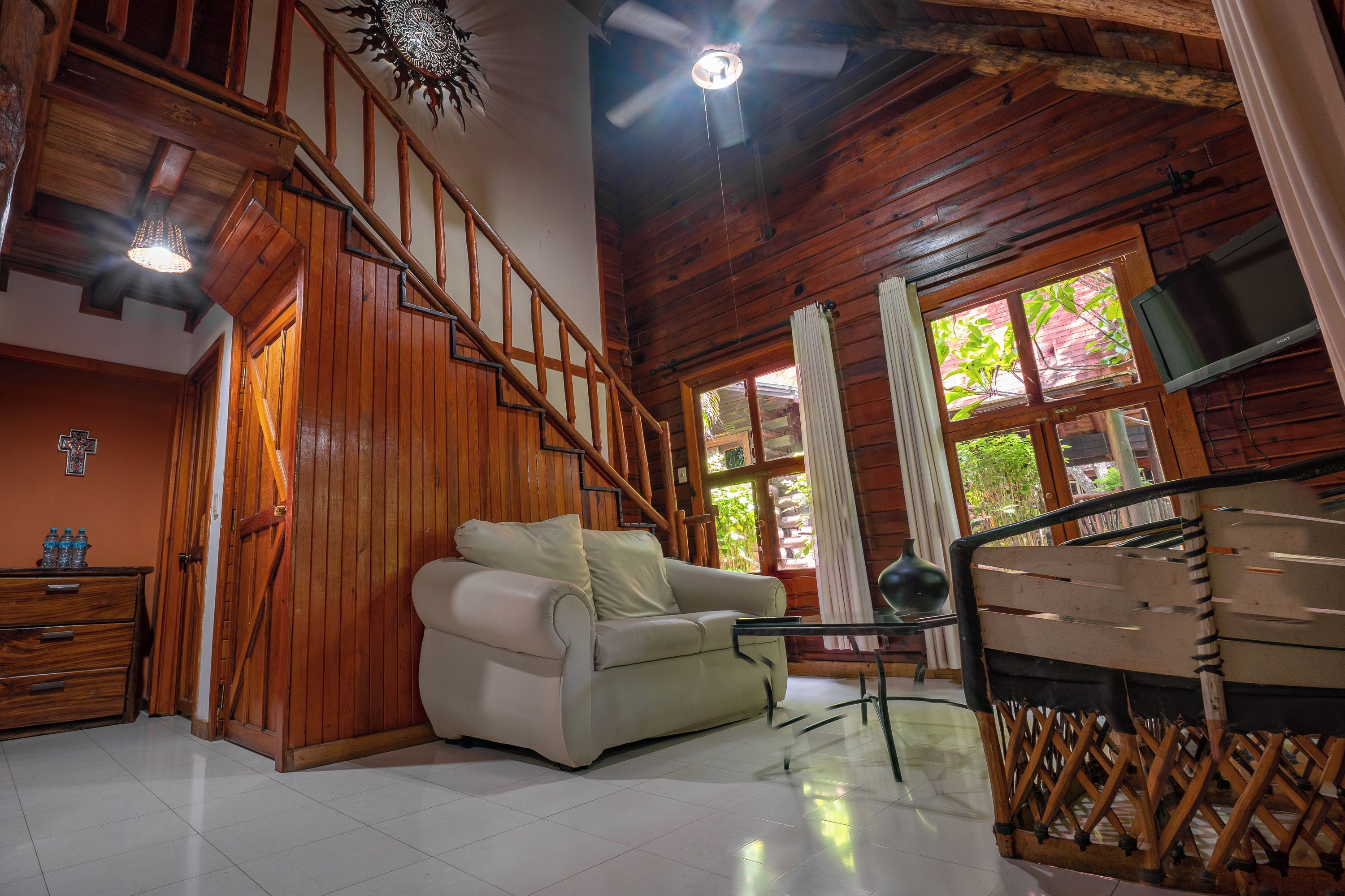 Un interior de madera con un sofá, una mesa de comedor y una escalera.