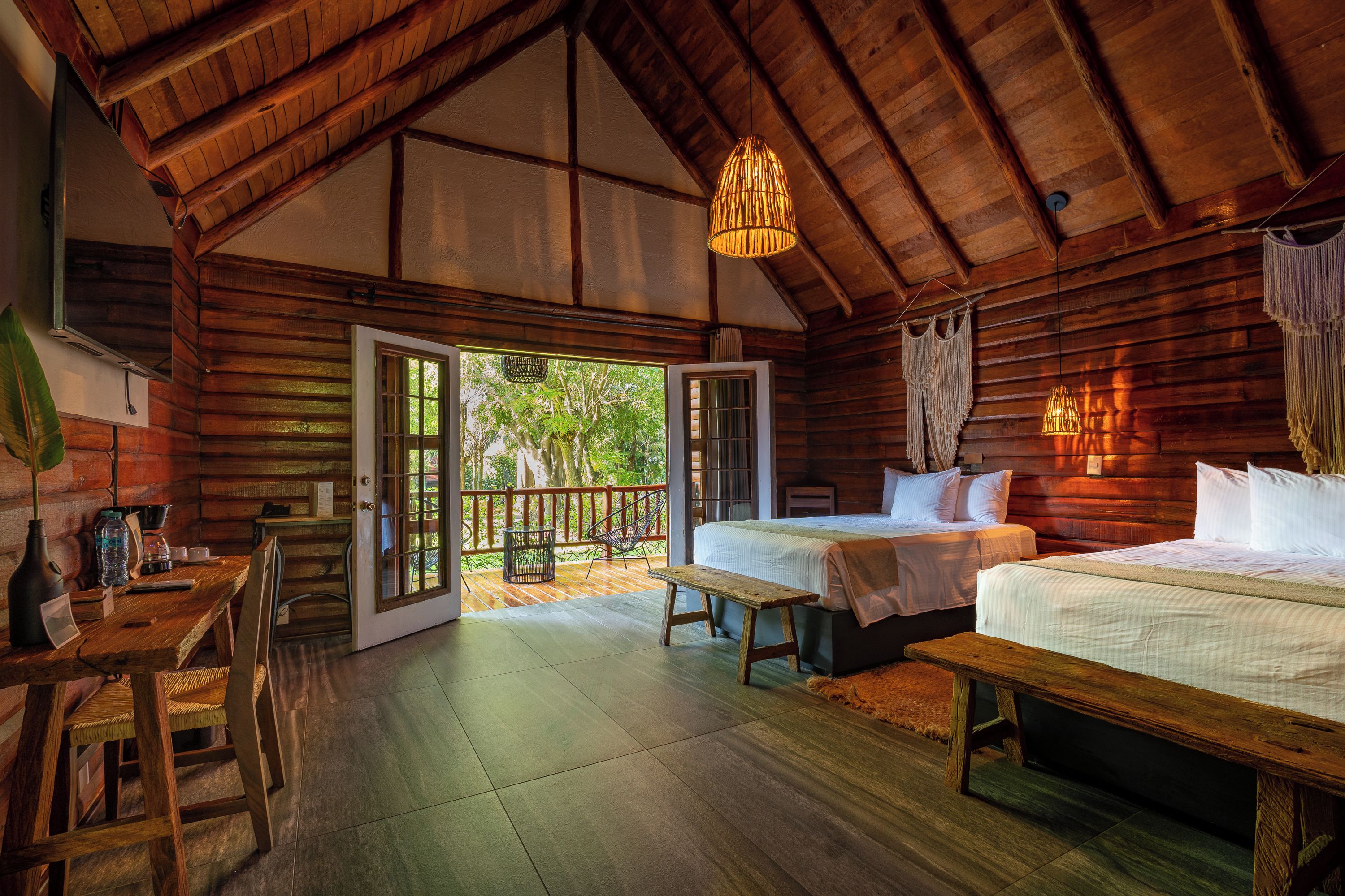 Una cabaña acogedora con interior de madera, un balcón con vistas y una cama con edredón blanco.