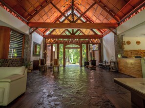 A spacious lobby with a high wooden ceiling, stone flooring, and a reception desk. -  Samao Resort (La Laguna)