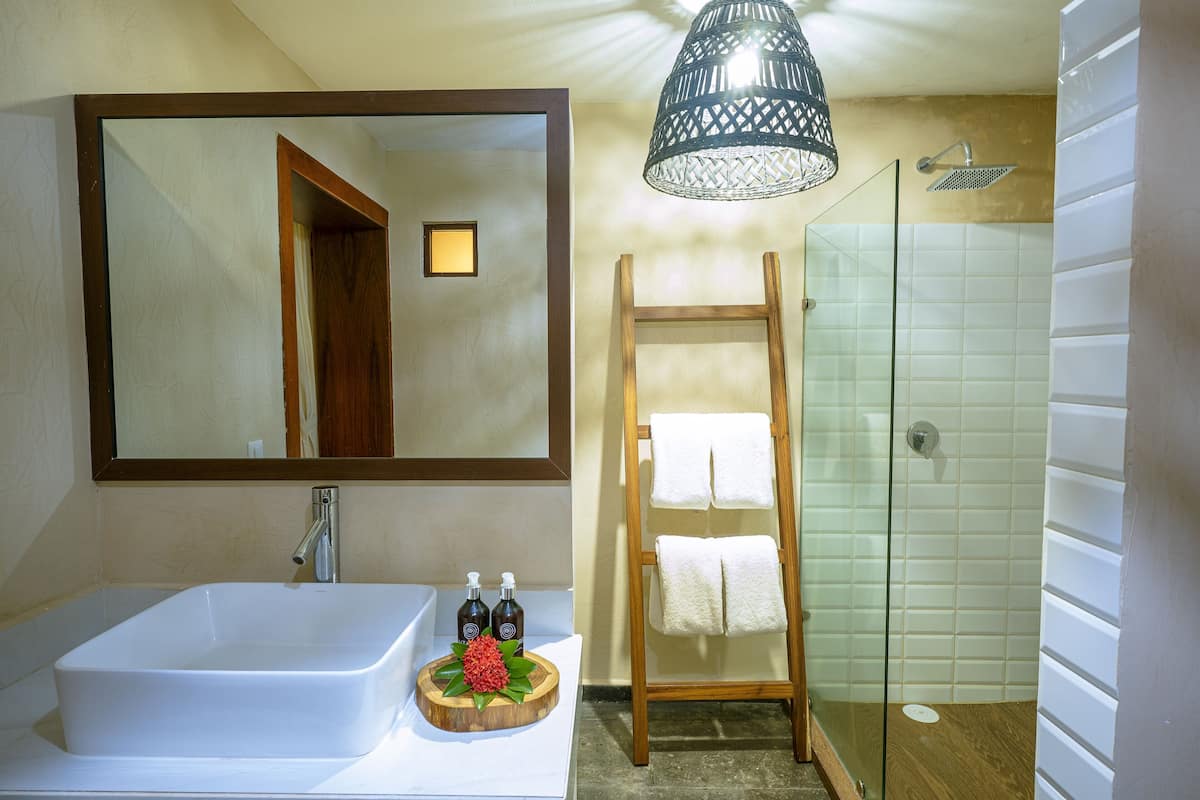 A bathroom with a large mirror, a bathtub, a wooden towel rack, and a glass-enclosed shower.