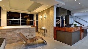 A modern hotel lobby with a large hot tub, a reception desk, and a staircase. - Porto Minas Hotel e Convenções (Uberlandia)