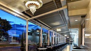 A modern indoor dining area with a long counter, multiple tables, and chairs. - Porto Minas Hotel e Convenções (Uberlandia)