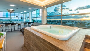 A modern bar area with a hot tub, large windows, and a city view. - Porto Minas Hotel e Convenções (Uberlandia)