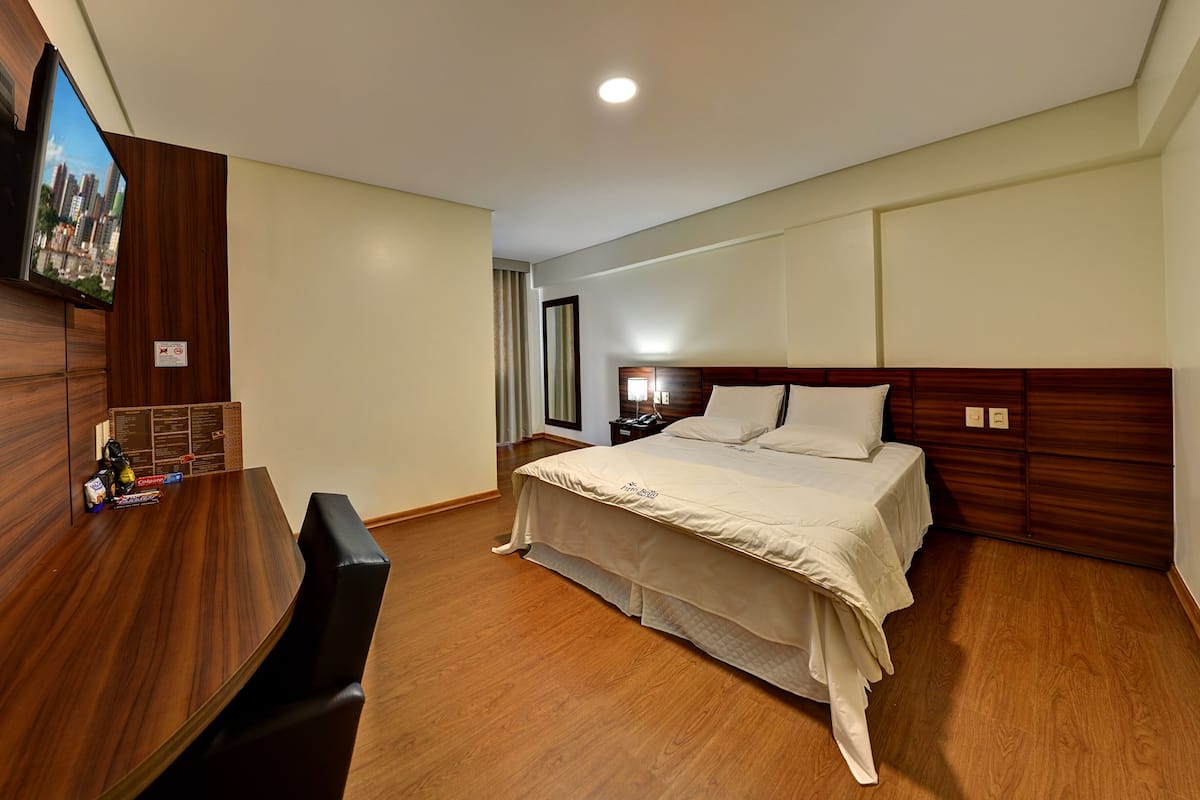 Une chambre d’hôtel équipée d’un lit, d’un bureau et d’un téléviseur fixé au mur.