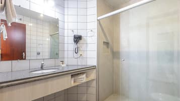 Une salle de bain moderne avec un grand miroir, deux lavabos, un porte-serviettes et une douche séparée par une paroi de verre.