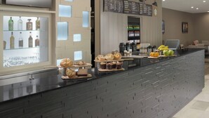 A modern hotel lobby with a reception desk, a menu board, and a beverage display. - Courtyard by Marriott Austin Pflugerville and Pflugerville Conference Center (Pflugerville)