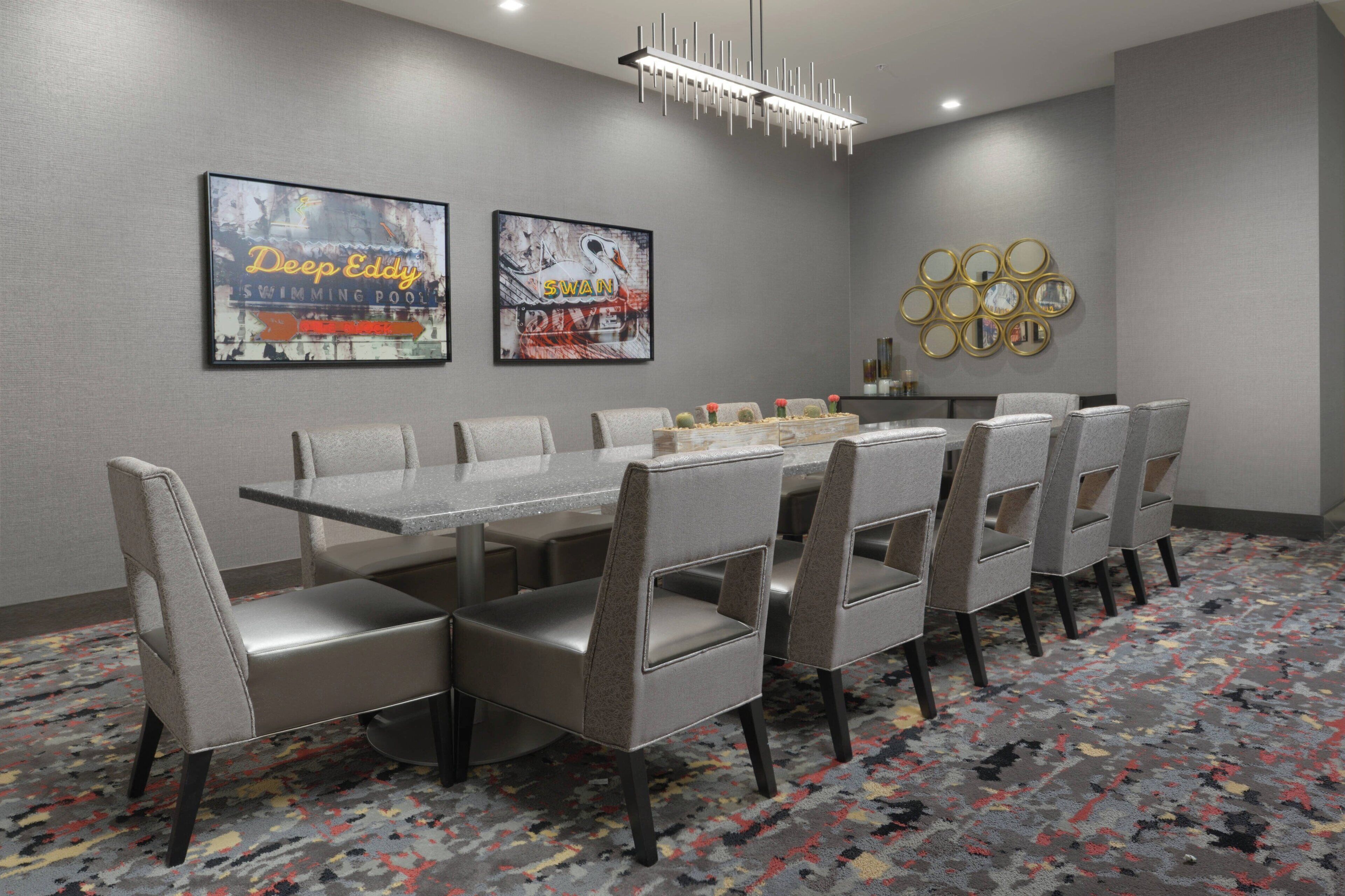 A conference room with a long table, six chairs, and a decorative wall with framed artwork.