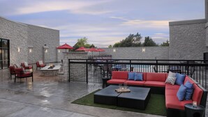 An outdoor patio with a red sofa, black ottoman, and red chairs. - Courtyard by Marriott Austin Pflugerville and Pflugerville Conference Center (Pflugerville)