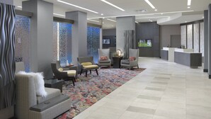 A modern lobby with seating areas, a reception desk, and a patterned carpet. - Courtyard by Marriott Austin Pflugerville and Pflugerville Conference Center (Pflugerville)
