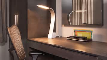 A modern desk with a sleek, curved desk lamp, a chair, and a mirror.