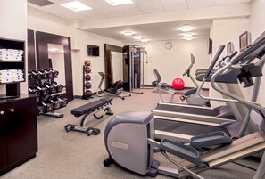 Un gimnasio con cintas de correr, mancuernas y equipo de ejercicio.
