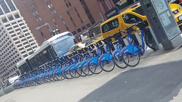 Een rij blauwe Citi Bike-stations in een stedelijke omgeving, met hoge gebouwen op de achtergrond.
