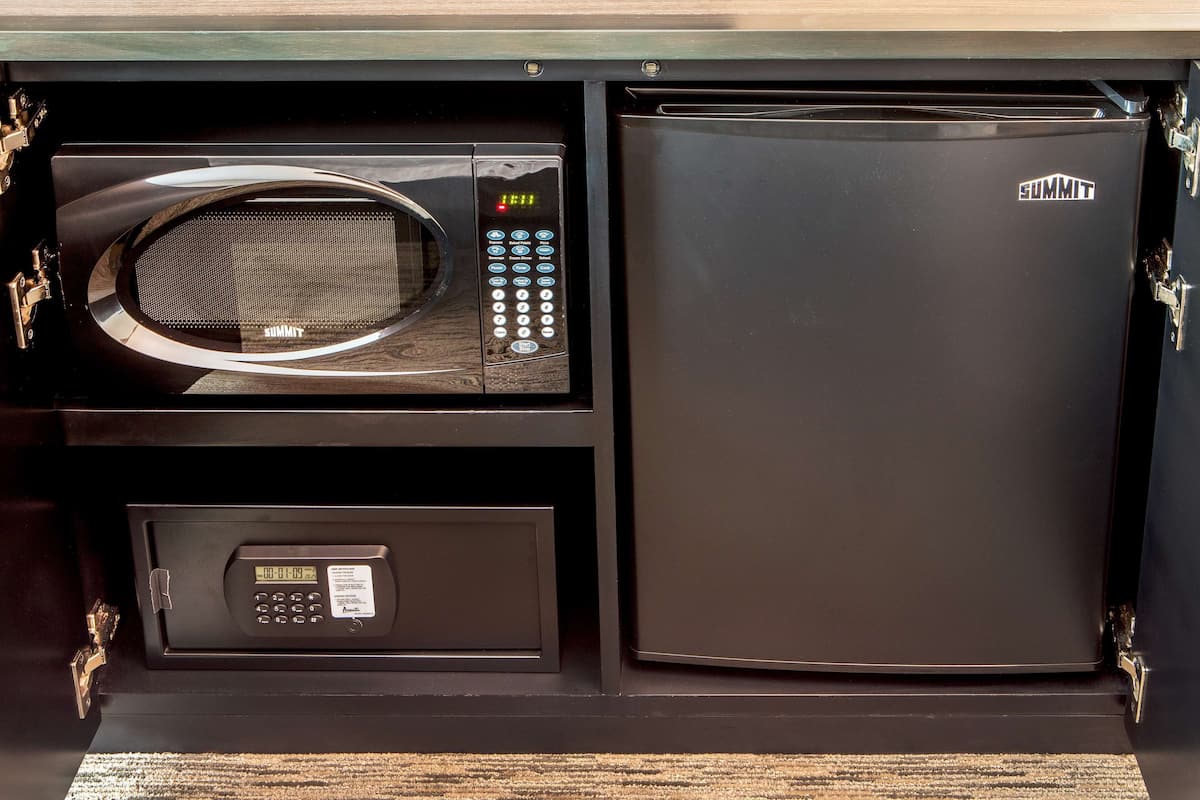 Un microondas y un refrigerador negros dentro de un mueble de cocina.