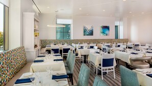 Un restaurante con varias mesas, sillas y un banco de colores con estampado.