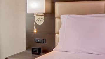 A neatly made bed with a white pillow and a headboard with a light fixture.