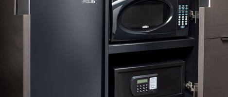 A black safe with a keypad and a digital display, and a microwave above it.