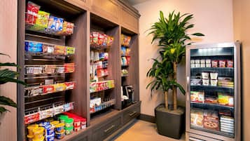 Un espace bien approvisionné, situé dans le hall d’un hôtel, proposant une variété de collations et de produits surgelés, notamment différentes marques de chips, de biscuits et de desserts glacés.