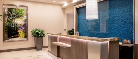 A reception area with a counter, seating, a large window, and a decorative wall.