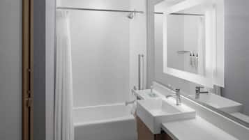 Une salle de bain moderne dotée d’une douche à parois de verre, d’une baignoire et d’un meuble-lavabo avec deux vasques.