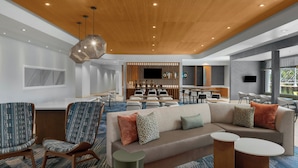 Un hall d’hôtel moderne doté d’un espace salon, d’un bar et d’un écran de télévision.