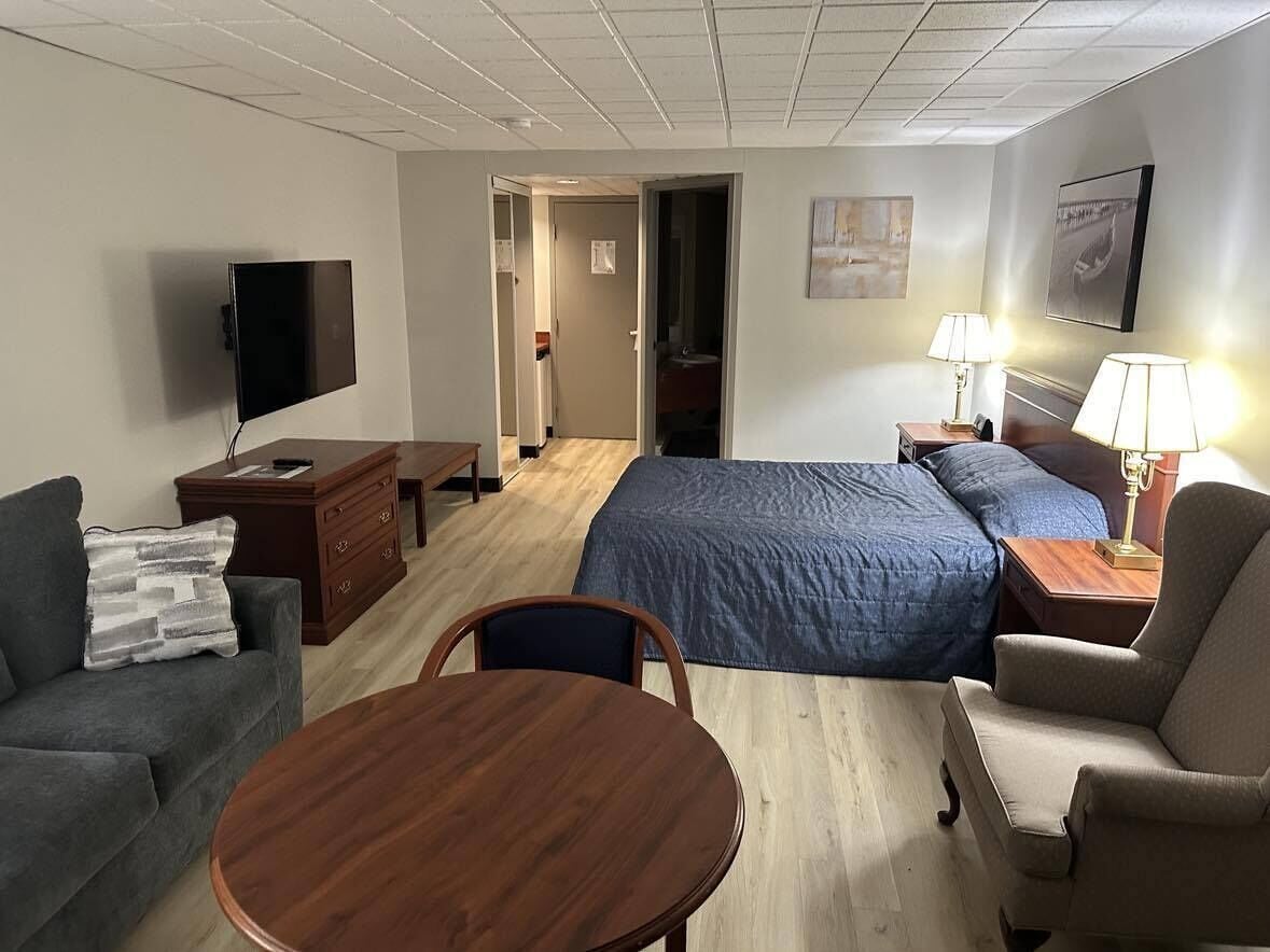 A hotel room with a bed, a sofa, a desk, a TV, and a dining table.