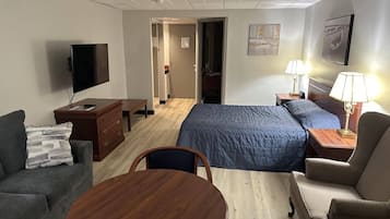 A hotel room with a bed, a sofa, a desk, a TV, and a dining table.