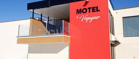 A modern motel with a prominent red facade and a balcony area.