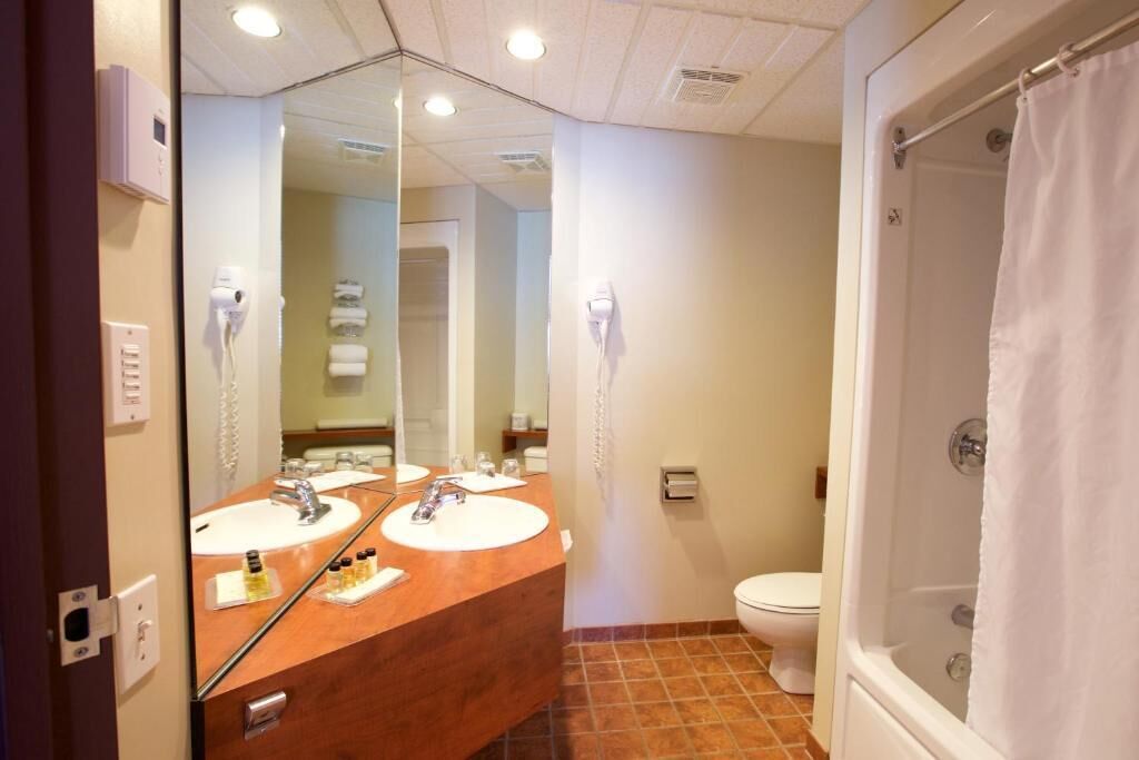 A bathroom with two sinks, a toilet, and a shower.