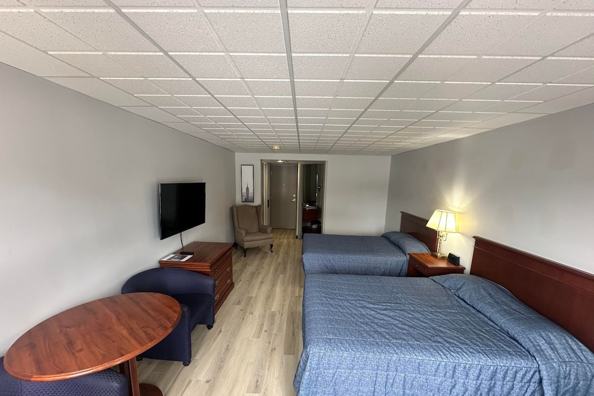 A hotel room with a bed, a TV, a desk, and a chair.