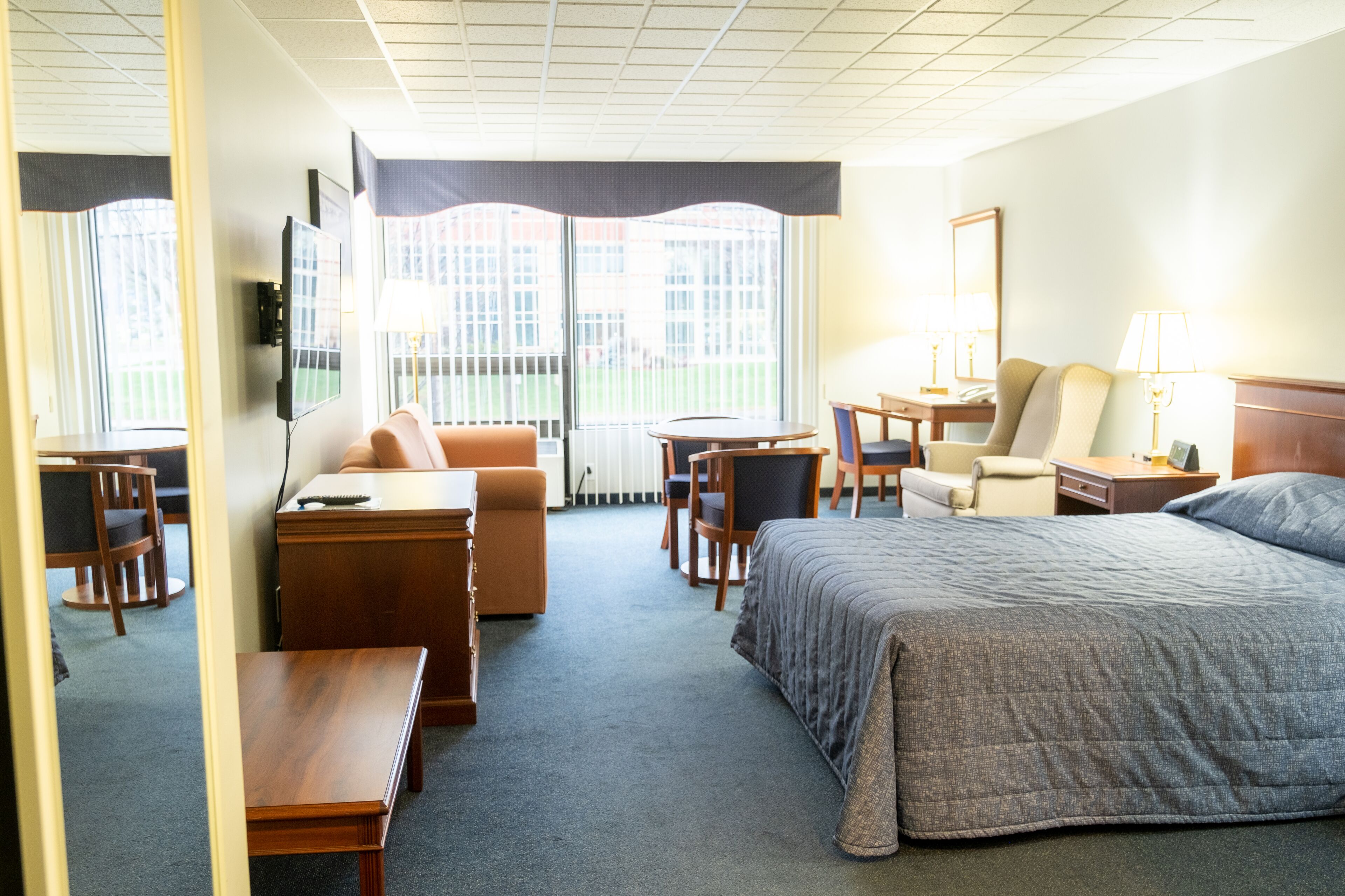 Una habitación de hotel con cama, escritorio, sillón, sofá y televisor.