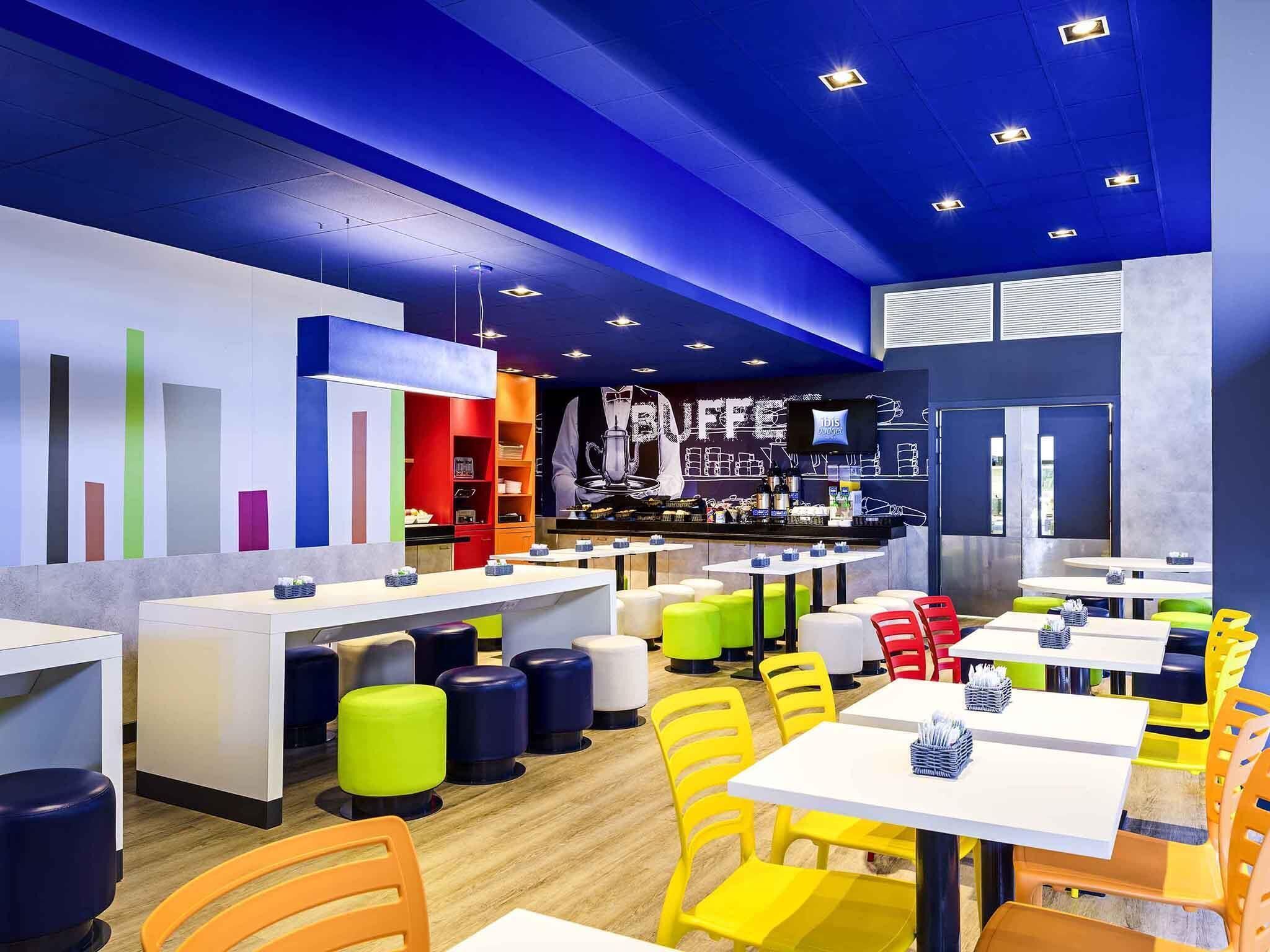 Un café moderno con taburetes, mesas y una barra de colores.