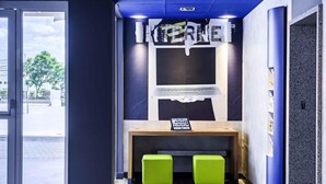 Un espace d’accueil moderne comprenant un comptoir, deux tabourets verts et un panneau fixé au mur.