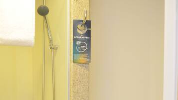 Un baño con puerta amarilla, ducha, inodoro y un cartel de AccorHotels.