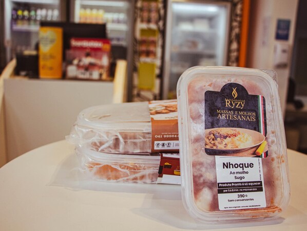 A packaged food item labeled 'Nhoque' on a table with other similar packages, in a setting that appears to be a store or a kitchen area.