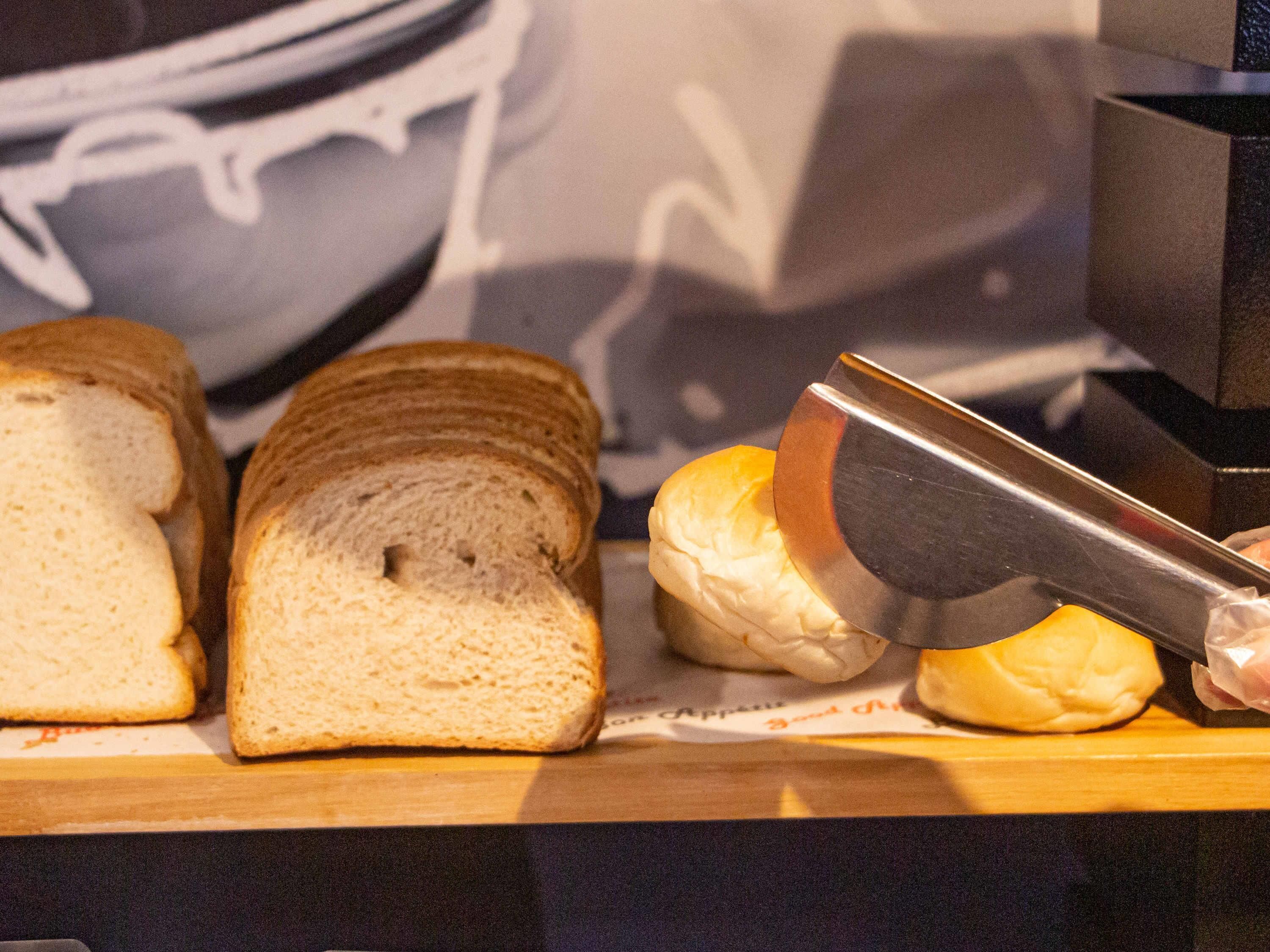 Slices of bread on a wooden cutting board with a knife.