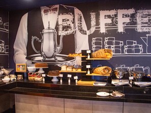Ein Buffet mit verschiedenen Speisen und einer großen Wandmalerei zum Thema Kaffee im Hintergrund.